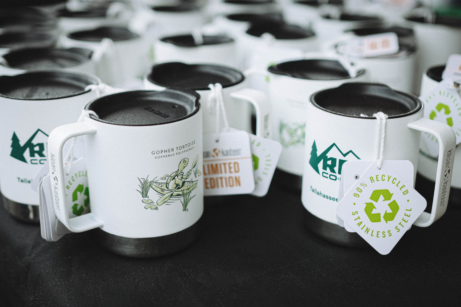 Limited edition REI Tallahassee mugs on a display table.